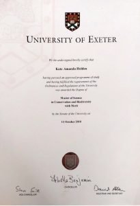 Photo of Master's Degree from University of Exeter for Kate Holden has a logo center top, writing in the middle and a seal stamp centered below