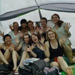 A group of young people sitting inside their tent, facing the camera.